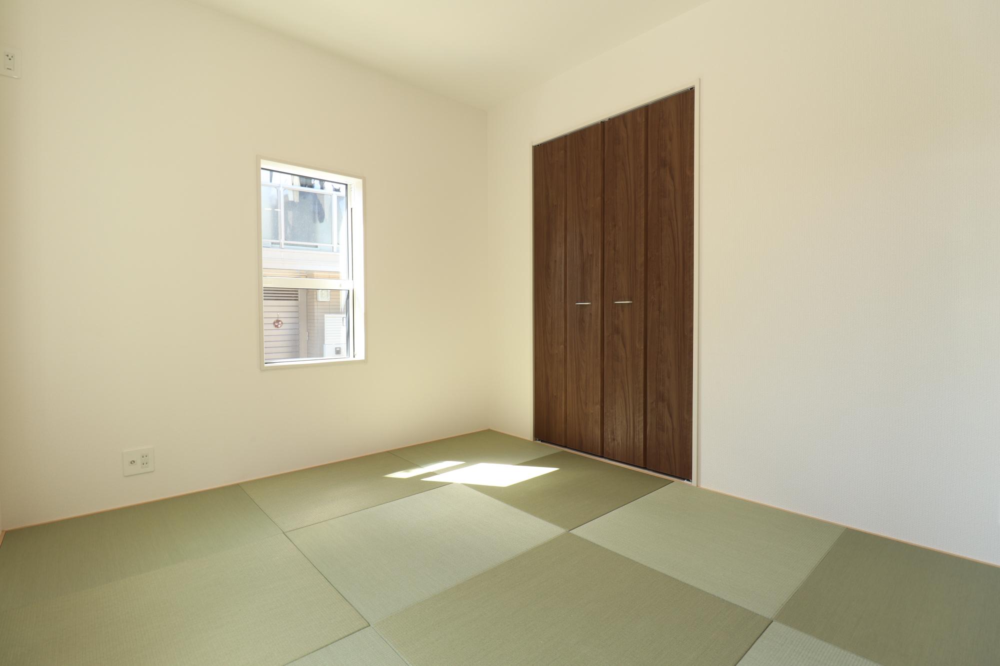 【1号棟和室(5.25帖)】　縁なしタタミを施した和室。収納スペースの扉には、木目調の折れ戸を採用しました。和と洋のテイストが調和する、モダンな空間です。