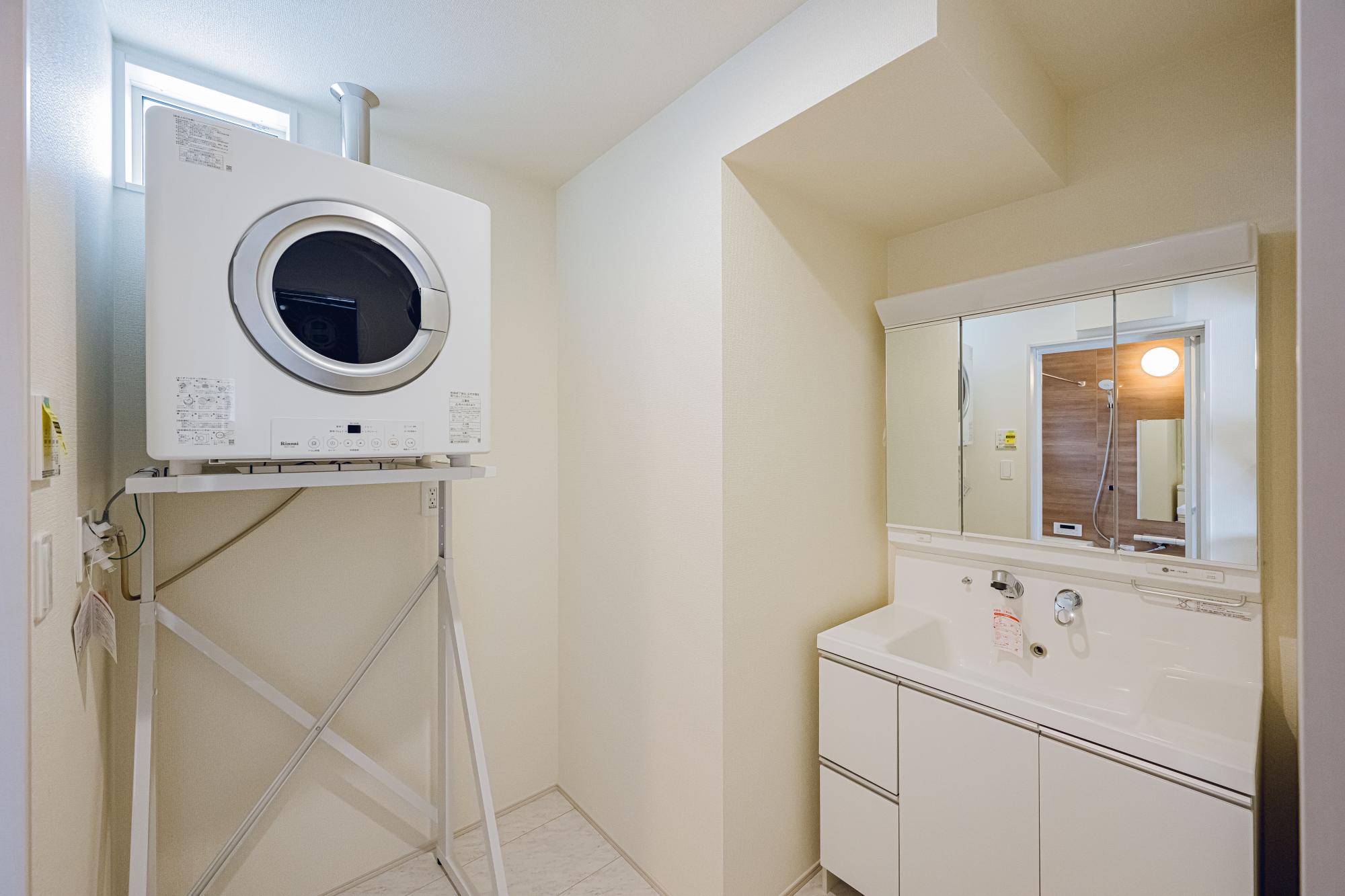1号棟　洗面スペース　水ハネ軽減やコップ等の置き場として900ワイド洗面化粧台。
 ガス衣類乾燥機は標準設置。