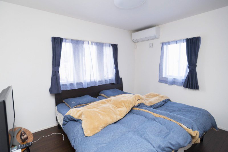 床や建具をダークブラウン、ファブリックはダークブルーのシンプルな色で統一した居心地のよい寝室