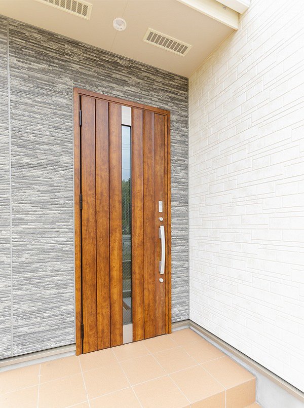 白とグレーのコントラストが美しい外観に、木目の玄関扉がアクセントに。