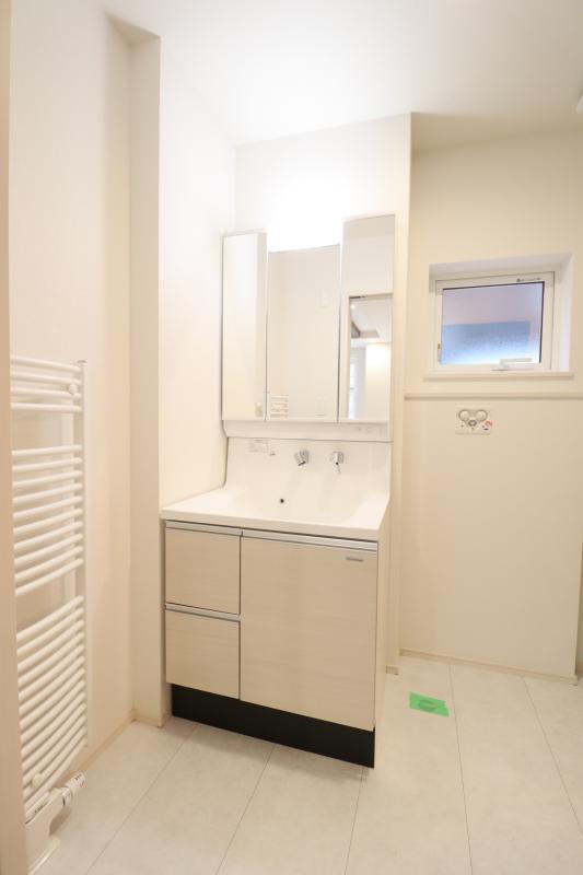 洗面室　洗面化粧台の左横にあるパネルヒーターは、タオルを乾かし温めるために利用できます。