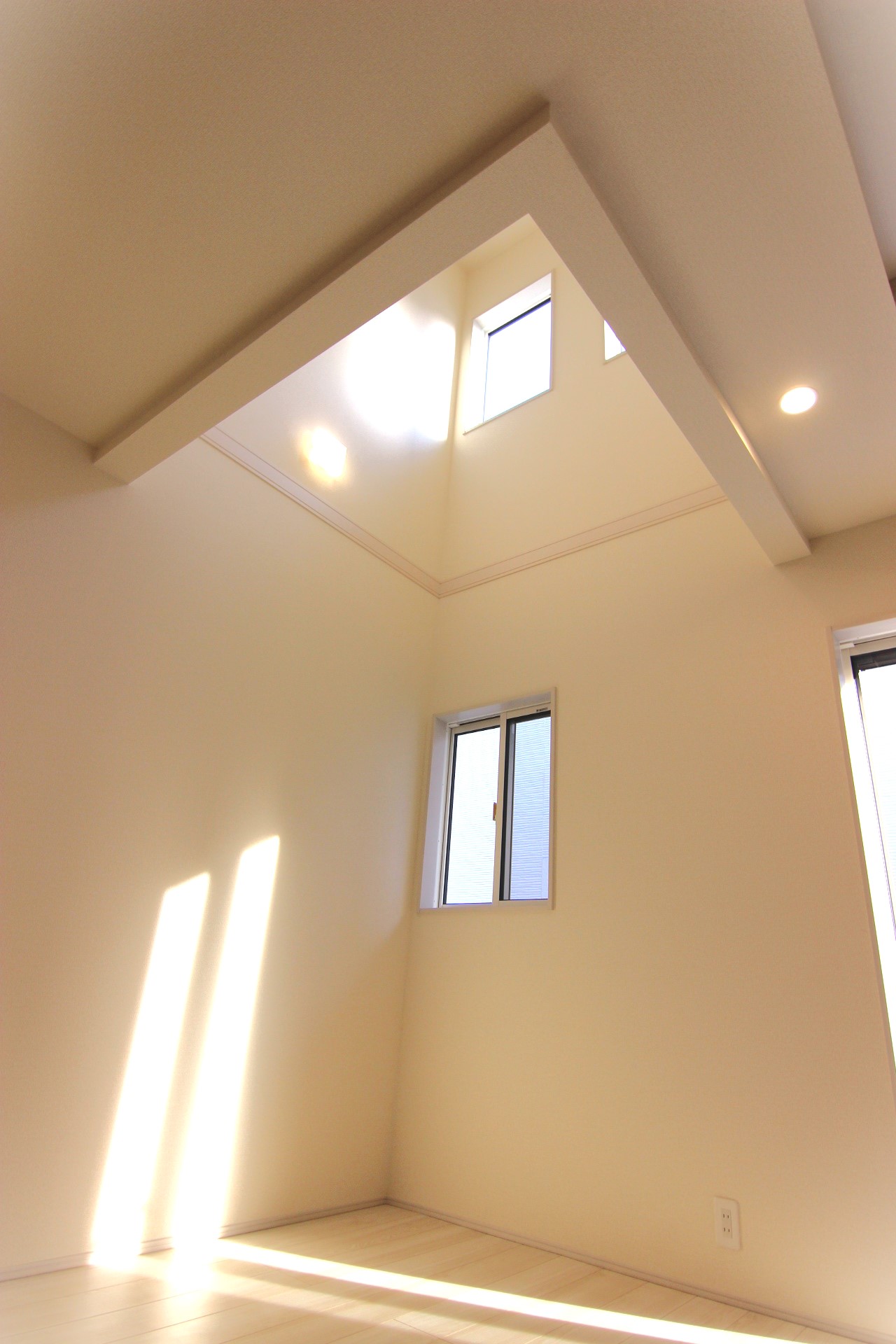 【6号棟:リビング内吹抜け】　高い天井の上部の小窓から光が差し込み、リビングを明るくさせ、開放感を演出します。