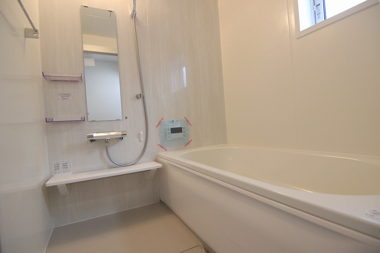 【浴室/10号棟】　ホワイトを基調とした爽やかな浴室です。便利な浴室乾燥機、シャンプーやボトル類を置ける棚、カウンターを設置しています。窓付きのため、湿気対策も◎