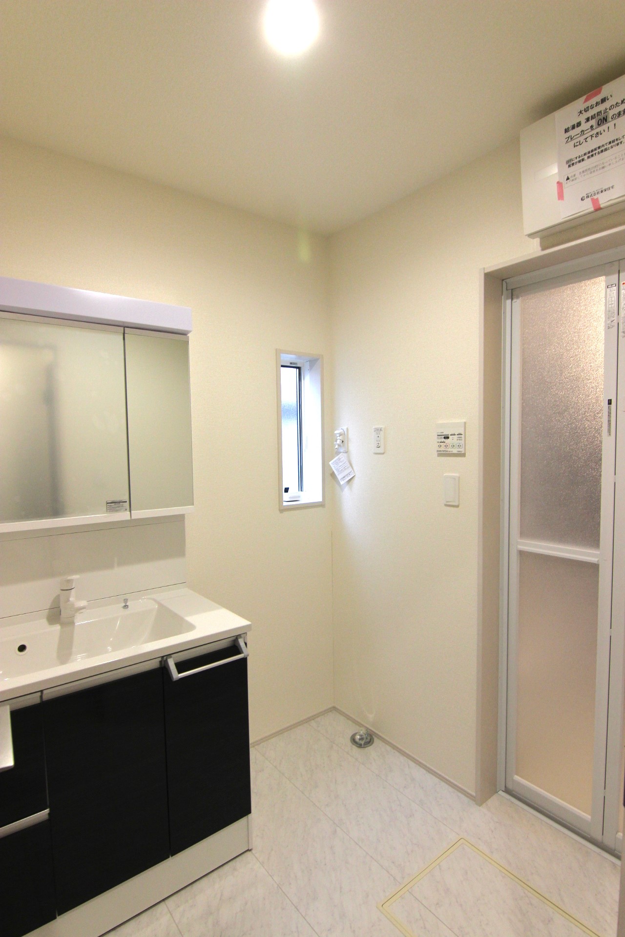 【1号棟:洗面所】　白を基調とした空間にシックなダークブラウンが映える清潔感ある洗面所。扉付き収納庫・床下収納付き。
