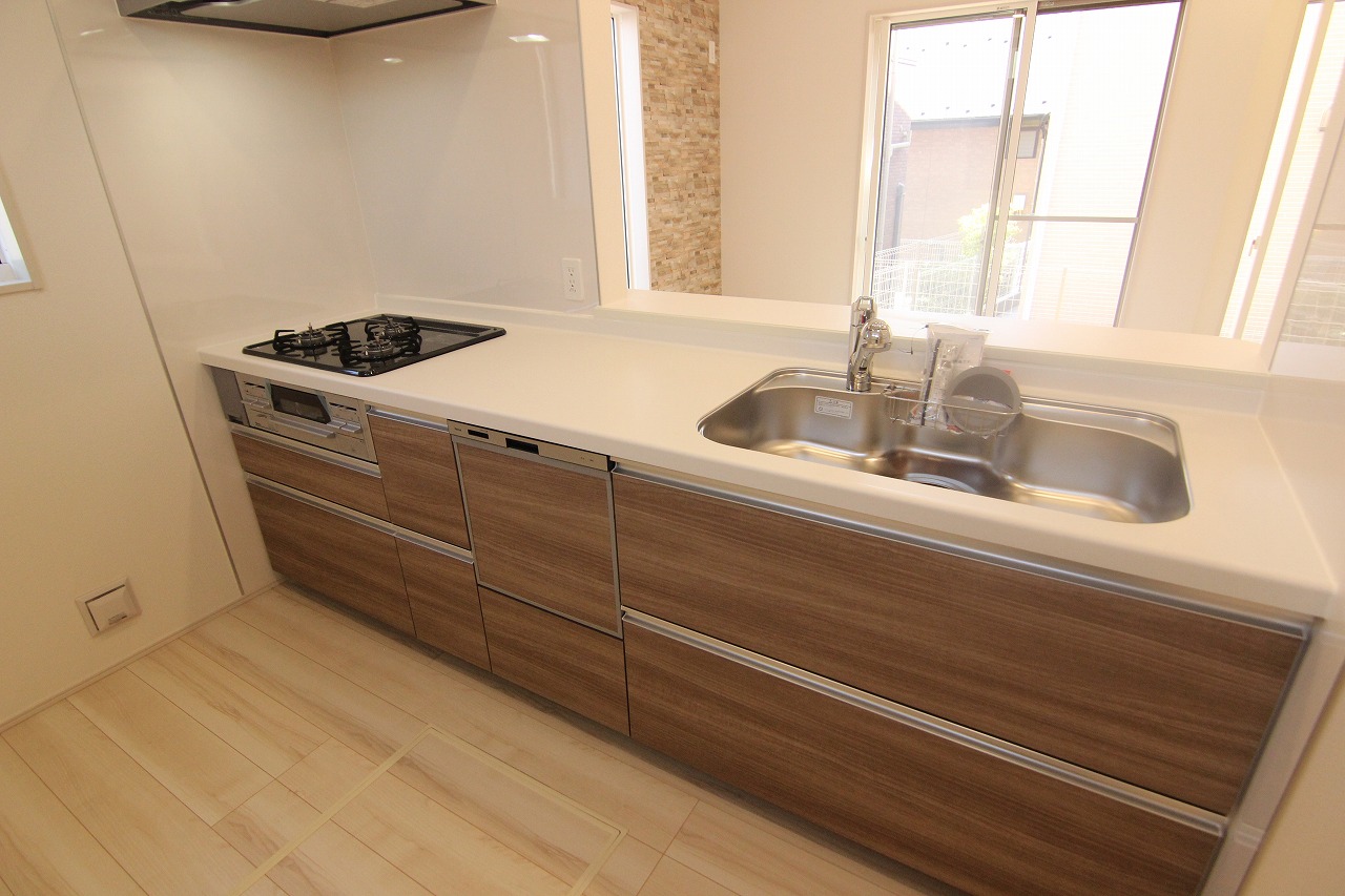 1号棟キッチン　LDKのナチュラルな雰囲気に調和するウッド調のキッチン。家事の負担を軽減してくれる食器洗乾燥機を搭載しています。