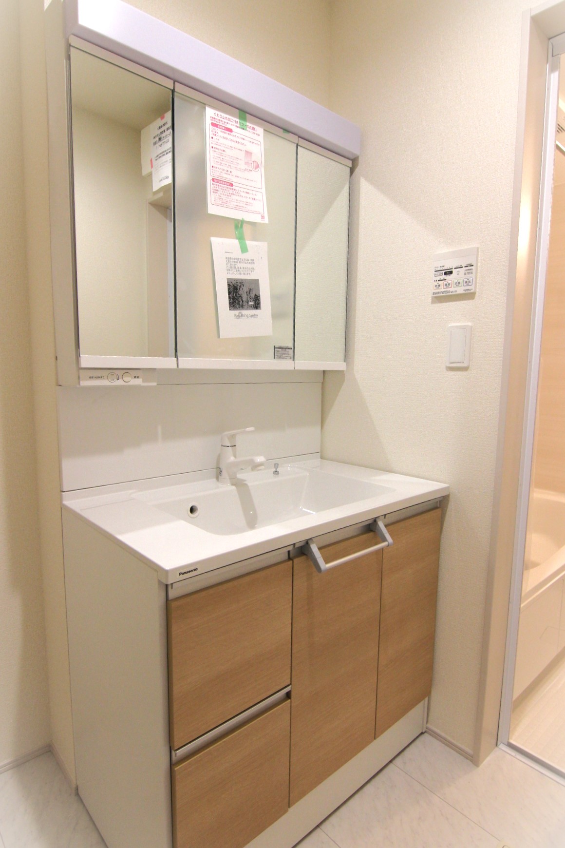 【2号棟:洗面台】　収納力に優れた3面鏡化粧台は、節水に効果的なカチット水栓!三面鏡の裏にはコンセント付き収納スペースになっています。中央の鏡は曇り止め仕様です。