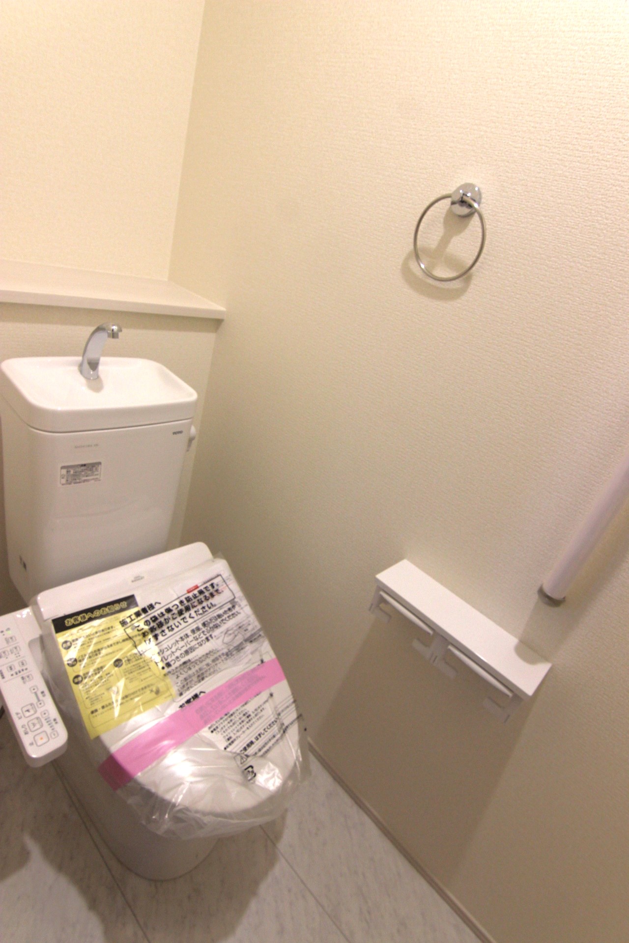 【1号棟:1Fトイレ】　多機能ウォシュレット・手摺り・壁面収納付き・背面には小物が置けるカウンターも付いています。