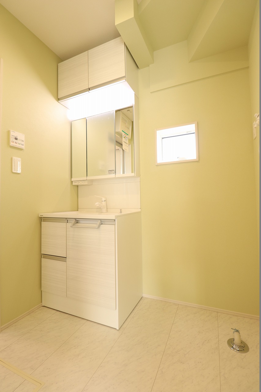 【1号棟/洗面室】　洗面化粧台は身支度の際に重宝する三面鏡タイプ。上吊戸棚、洗面ボウル下、三面鏡裏に収納スペースがあります。水回りの距離が近く、家事動線良好です。