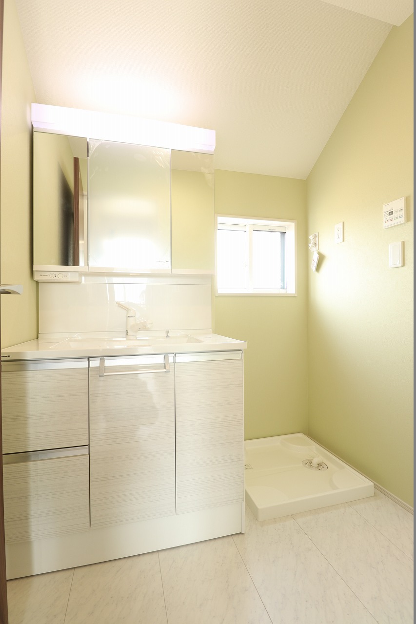 【2号棟/洗面室】　パステルカラーのクロスを施した清潔感のある洗面室です。洗濯動線が快適な2階配置を採用しました。洗濯後、そのままバルコニーへ干せるため、家事の時短にも繋がります。