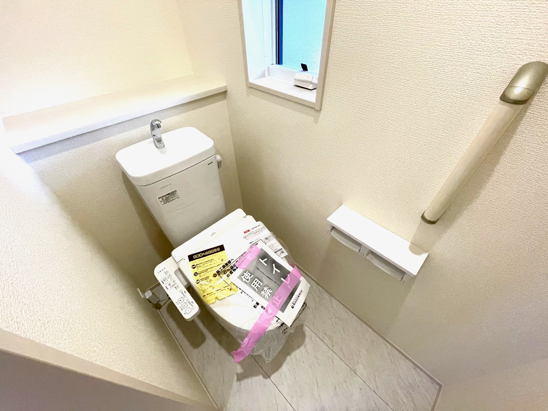 【2号棟1階トイレ】　多機能ウォシュレット・手摺り・壁面収納付き・背面には小物が置けるカウンターも付いています