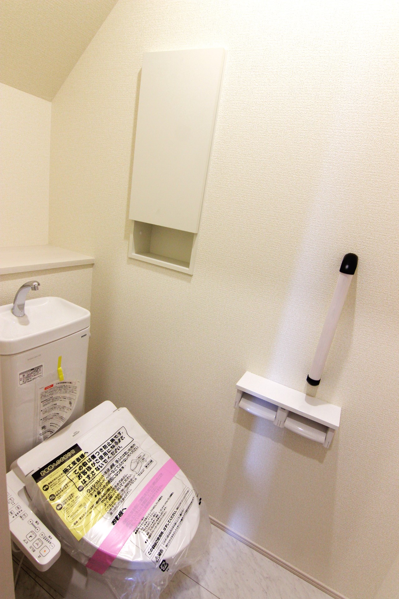 【1号棟1Fトイレ】　多機能ウォシュレット・手摺り・壁面収納付き・背面には小物が置けるカウンターも付いています