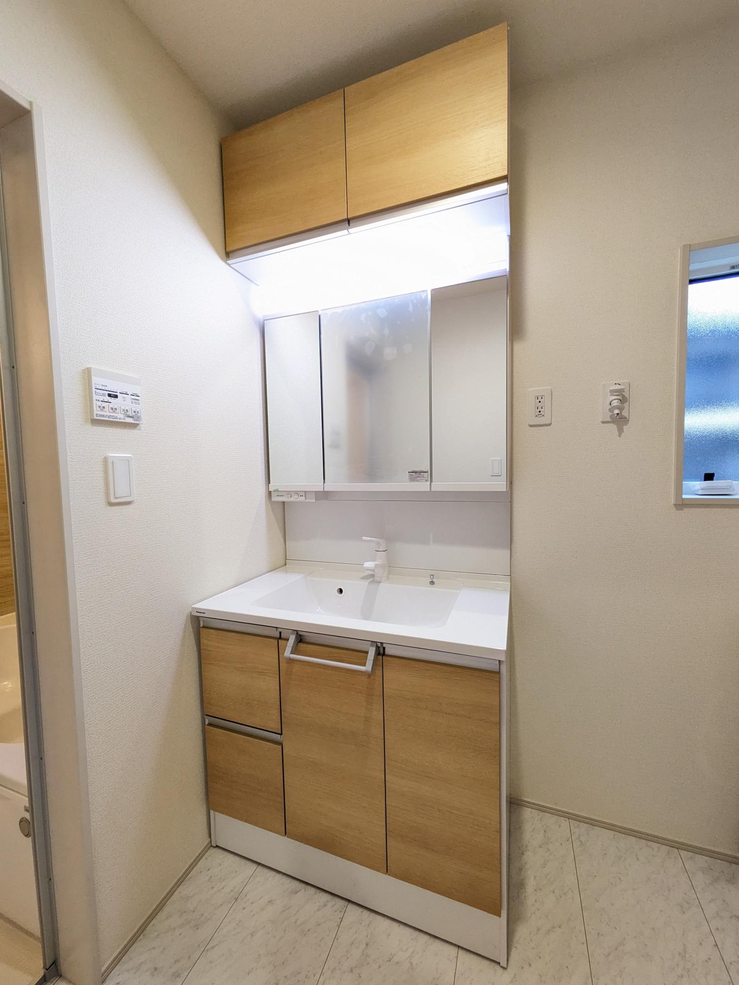 洗面所　ナチュラルカラーでまとめられた洗面所は、横幅が900mmワイドの三面鏡付きで朝の身支度もラクラク。吊り戸もあり収納スペースにも困りません。