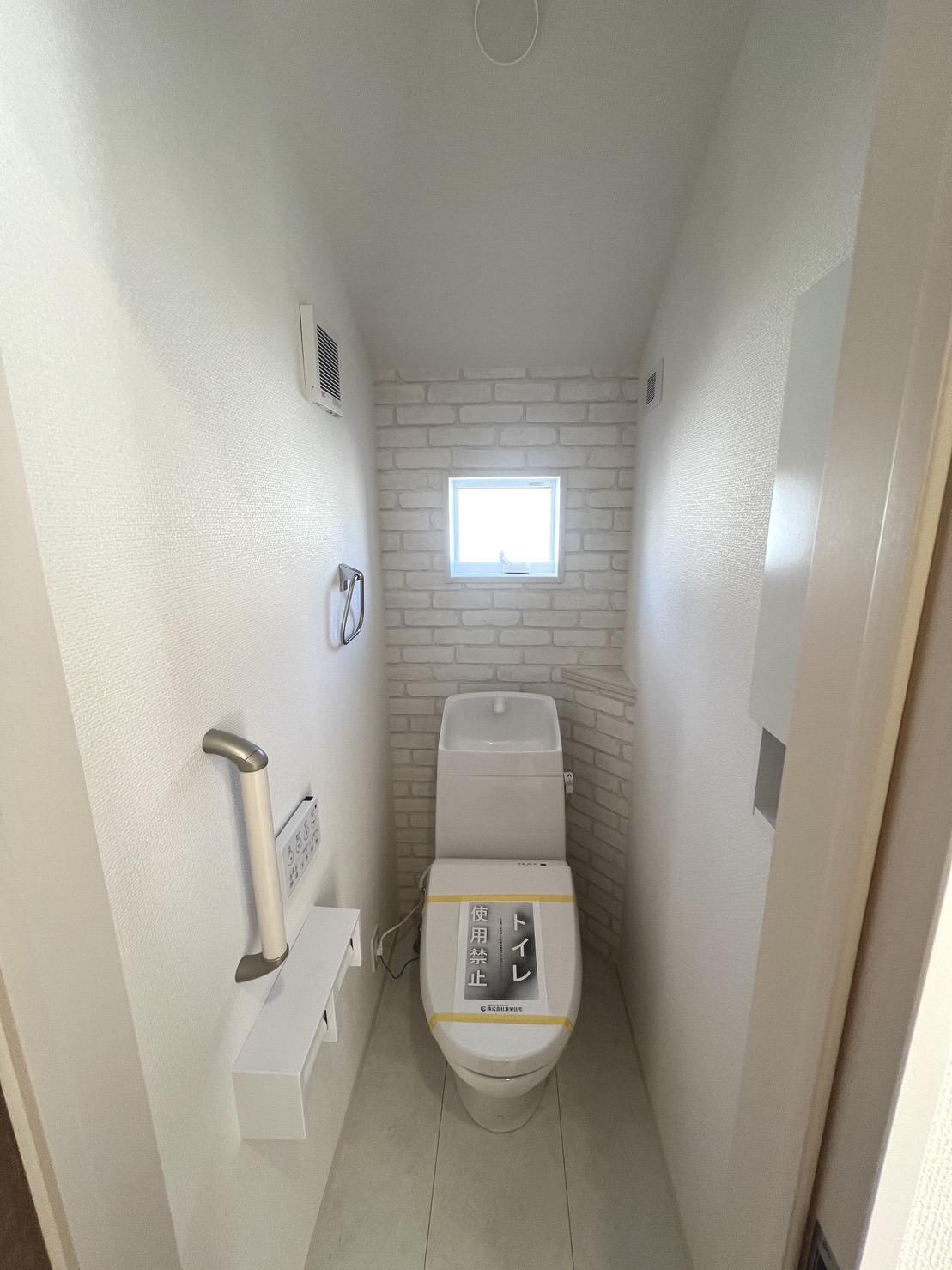 【2階トイレ】壁への水はねを防ぎ手洗いしやすい形状のトイレタンク。殺風景になりがちなトイレにも温かみのあるアクセントクロスを選択しています。