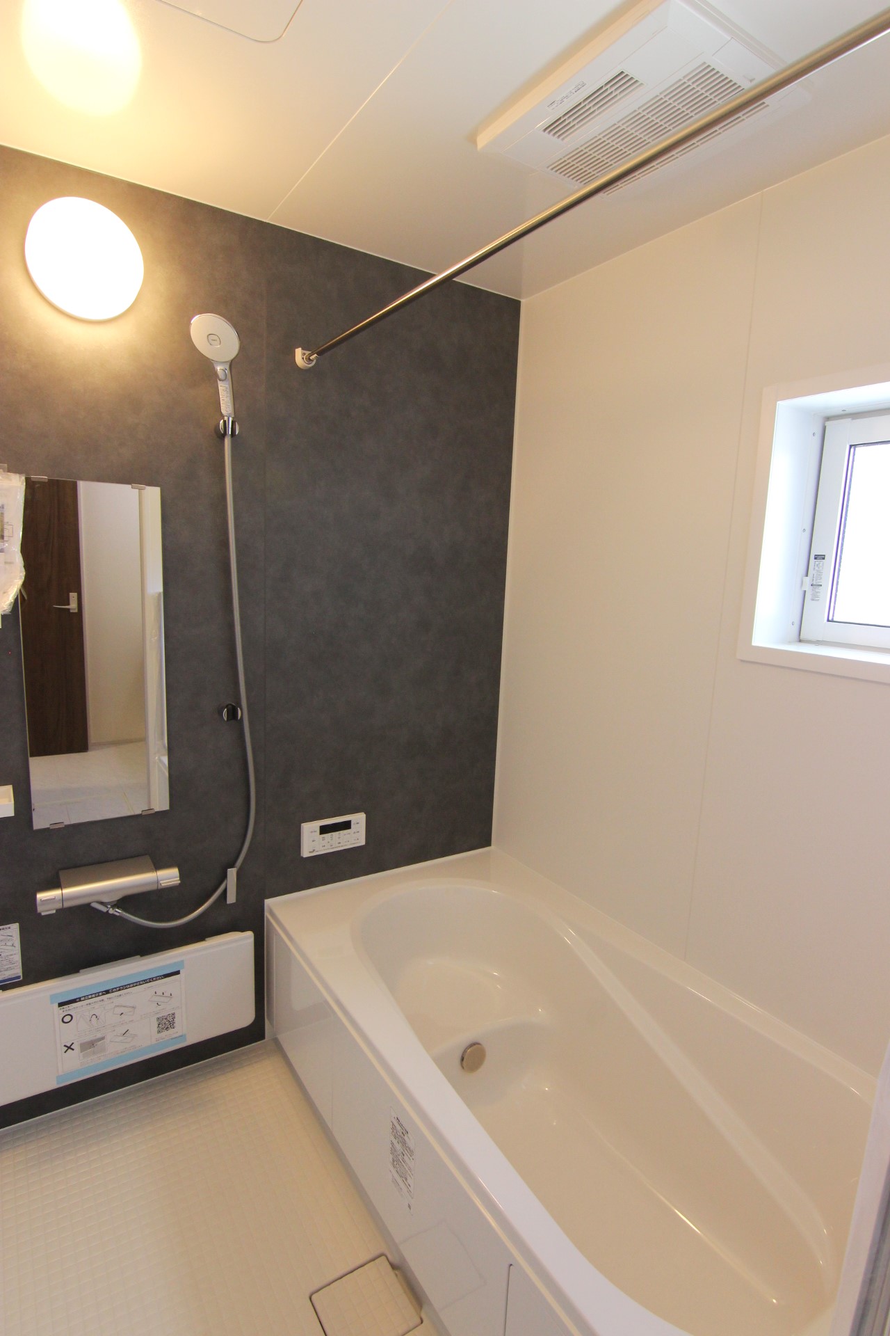 【3号棟:浴室】　白を基調とし、モルティオダークの壁を一面に敷いたシックな雰囲気の浴室。吐水/止水の切換えが手元で操作できるエコアクアシャワーは節水仕様で省エネです!※浴室機能は全棟共通です