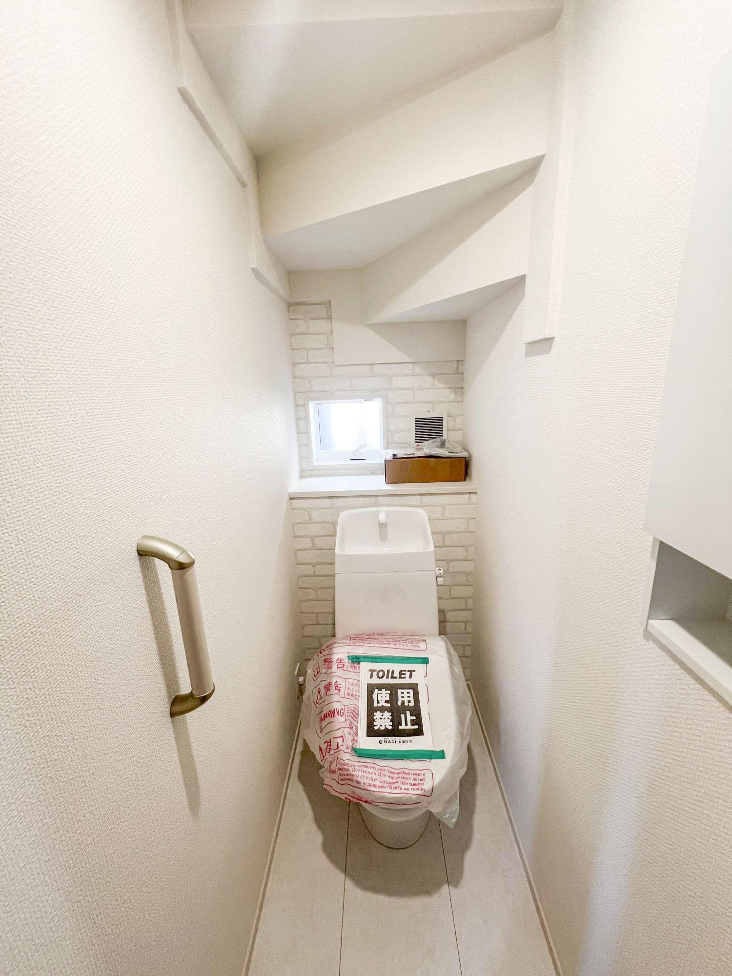 【1階トイレ】外の光が入る小窓、手すりカウンターが設置されています。