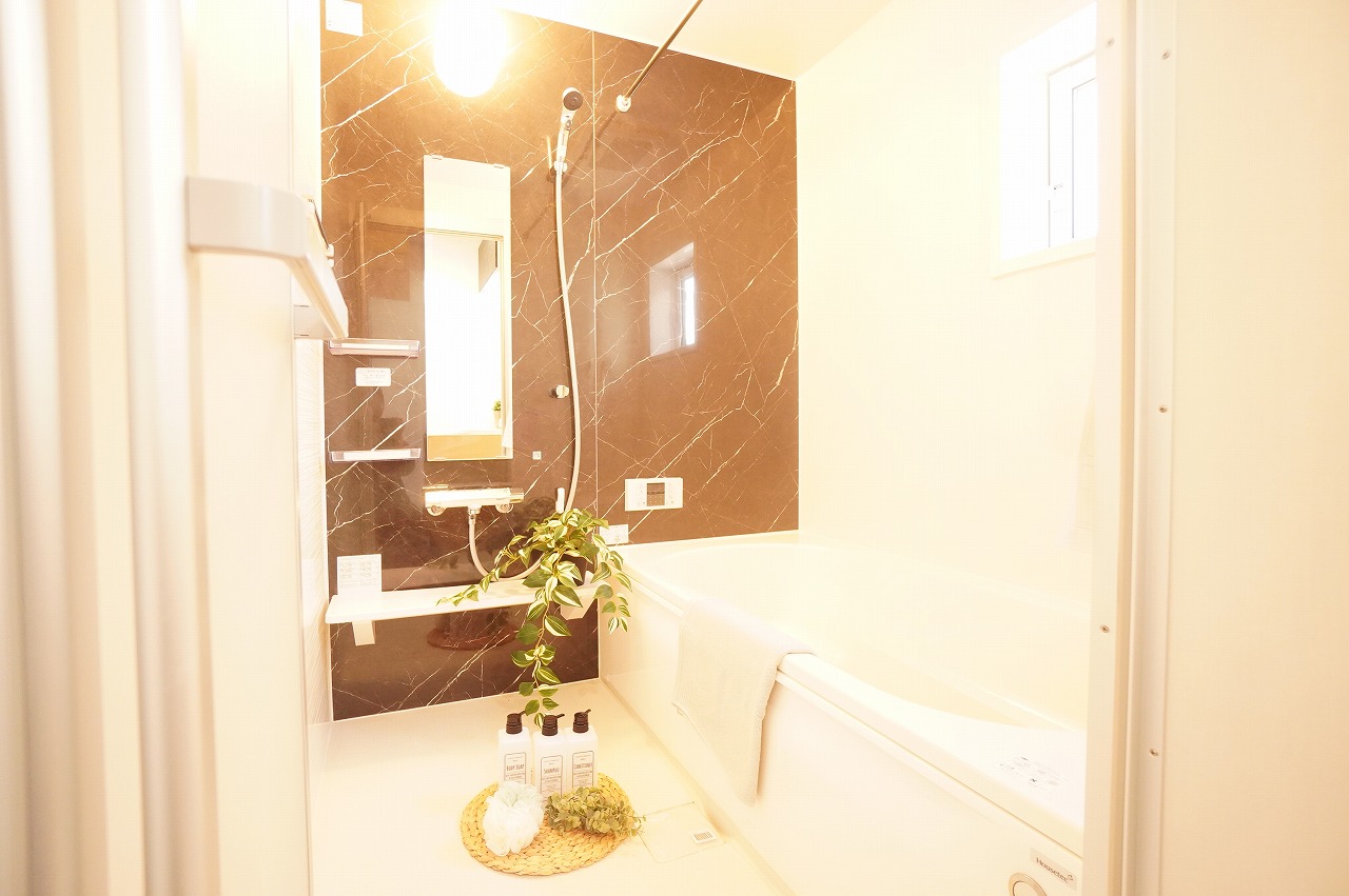 【浴室/11号棟】　大理石調のアクセントパネルを施した浴室です。浴槽・洗い場ともに開放感のある広さのため、お子様との入浴時も快適です。浴室暖房換気乾燥機、棚、カウンターを採用しています。