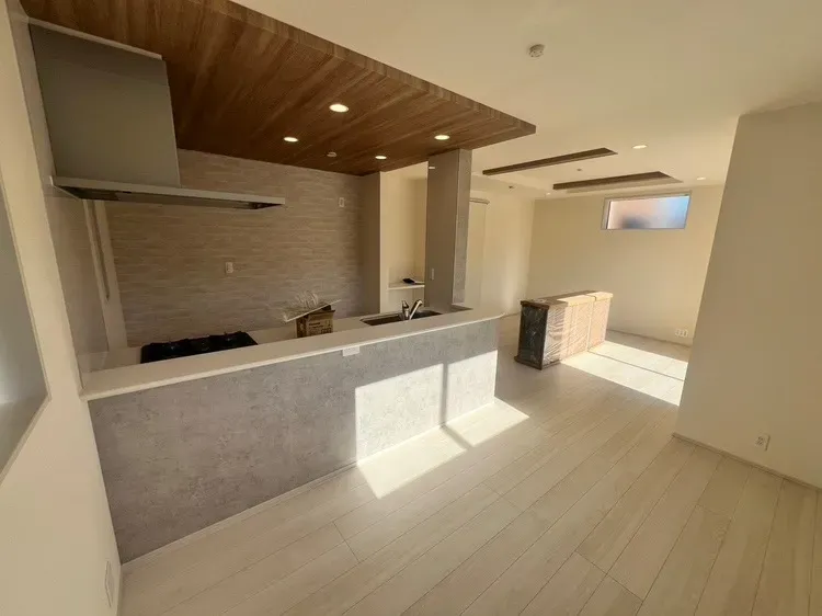 木目調のポップアップキッチンは天井デザインで空間を仕切り、メリハリを演出。※完成前の写真です【3号棟】