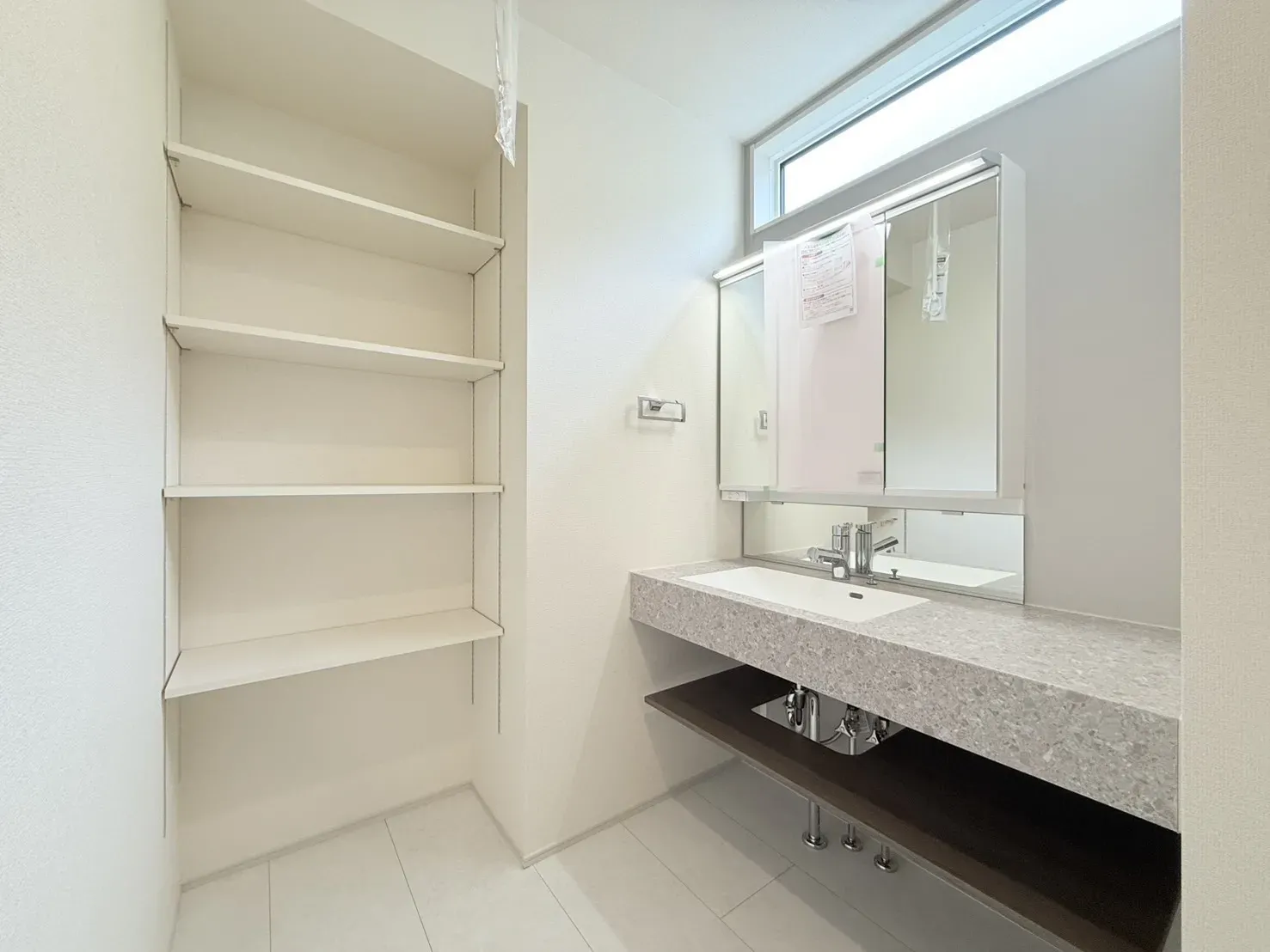 【洗面化粧台】ホテルのようなオシャレなデザインが特徴的な洗面化粧台。継ぎ目がないカウンターとオープン収納を採用しお手入れのしやすい仕様となっております。