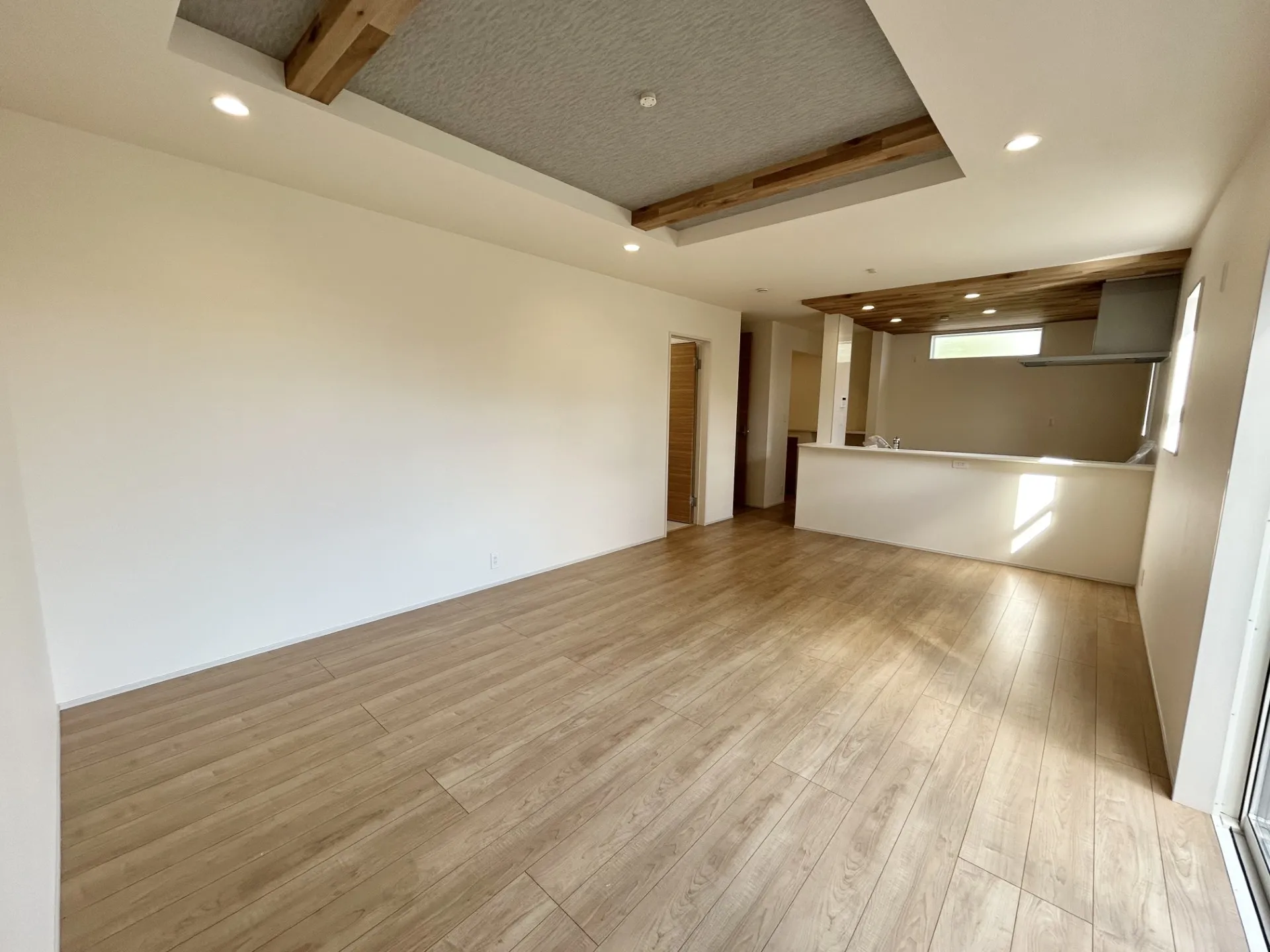 【②号棟】キッチン部分と折上天井の梁部分に同一の木目調のアクセントクロスでリビングに統一感を出しました