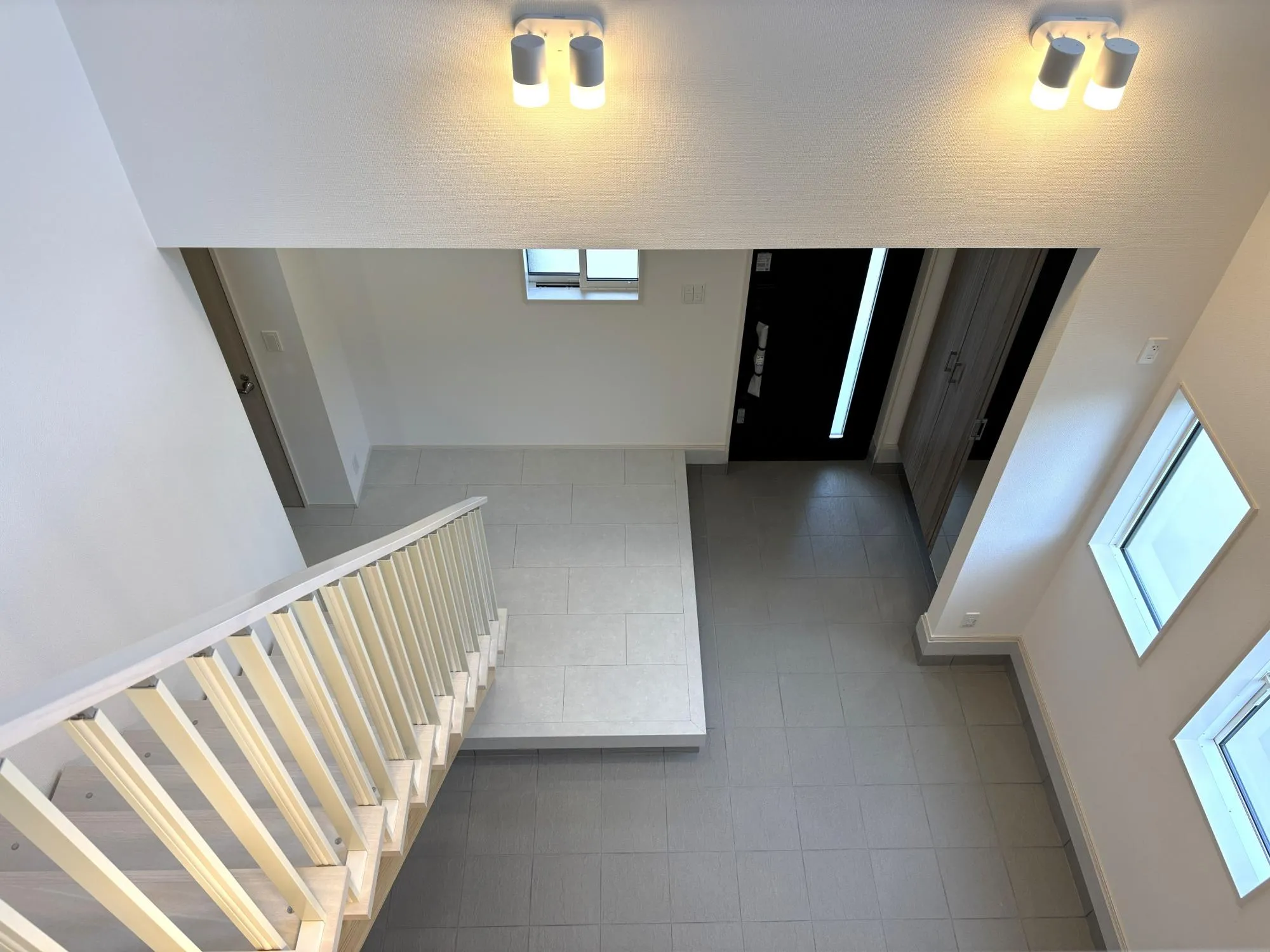 【玄関吹抜(2号棟)】玄関に吹抜を設け、扉を開けた瞬間に広がる開放的な空間。自然光がやさしく差し込み、住まい全体を明るく迎える印象的な玄関です。