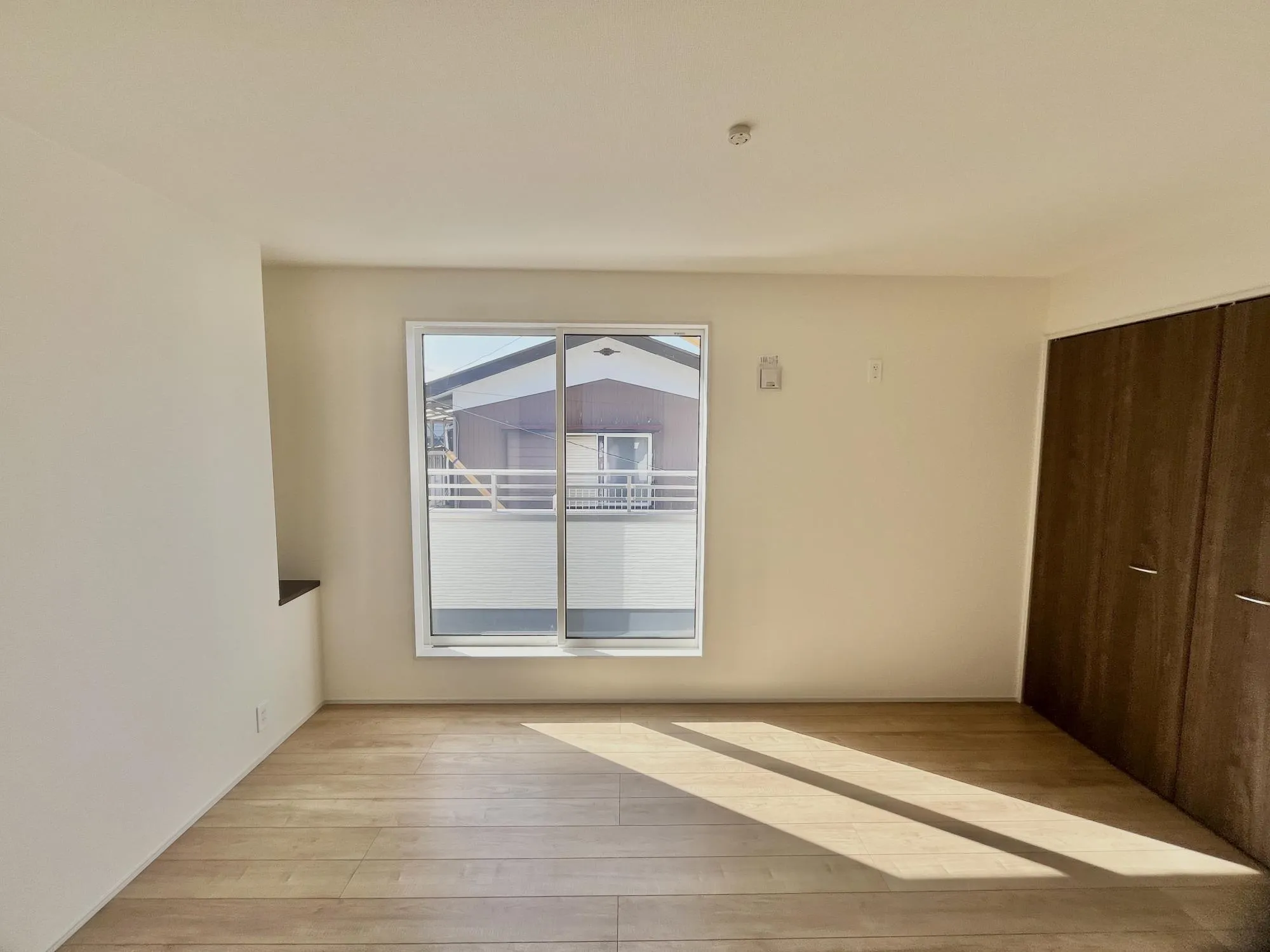 大きな窓のあるバルコニーに面した洋室。日差しがたっぷり降り注ぐ、居心地のよい空間です