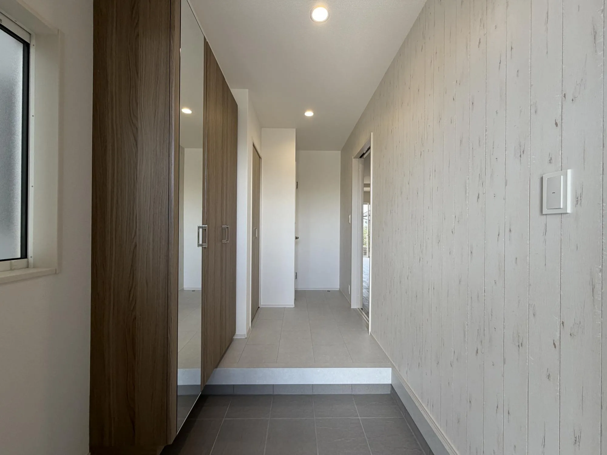 【玄関1号棟】入って左側にアクセントクロスを設け落ち着いた雰囲気のある玄関です。