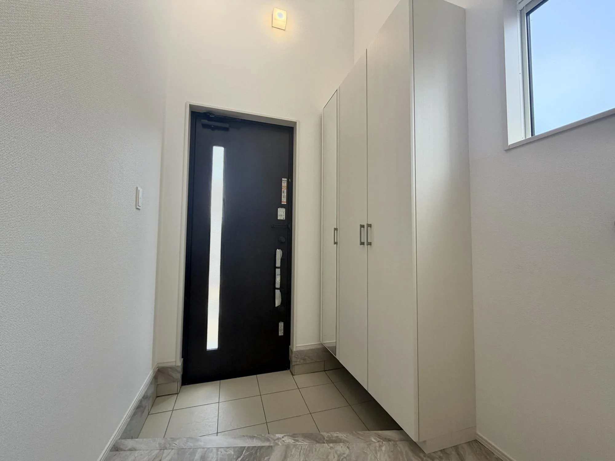 【玄関2号棟】白基調で明るい雰囲気の玄関です。上部は吹抜で開放感があります。