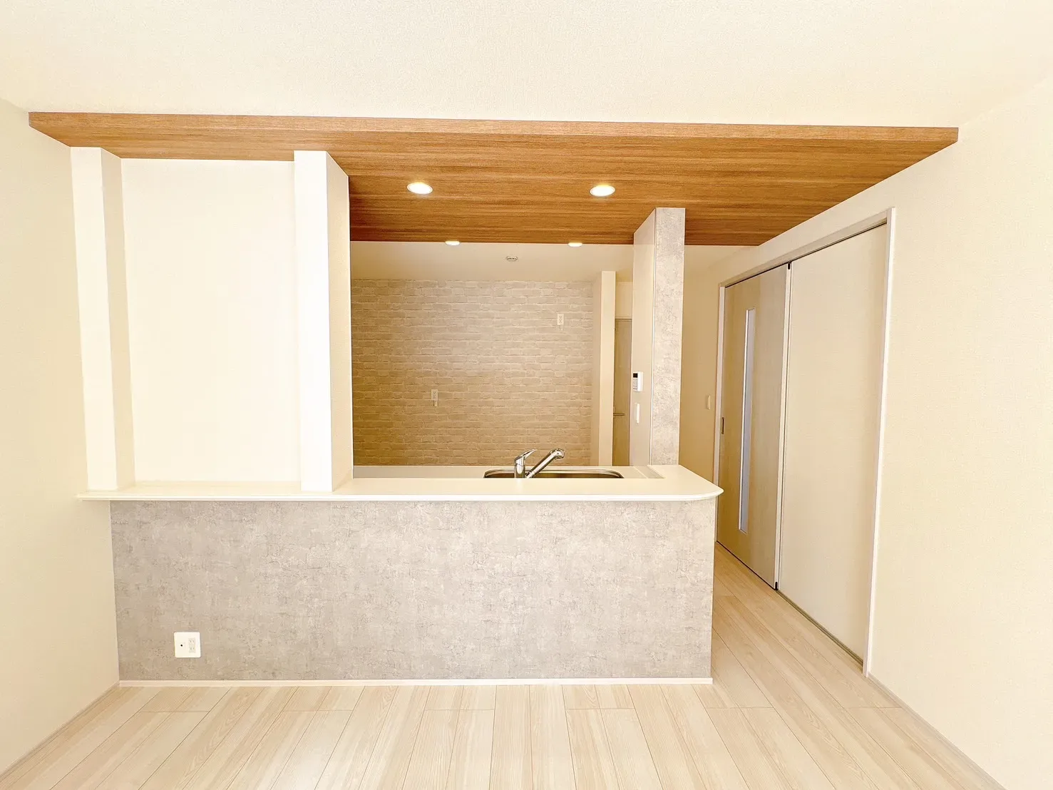 【キッチン前面】ご家族やゲストと会話が弾む対面式キッチンを採用。キッチン上部は空間にメリハリを演出するポップアップ天井を施しています。