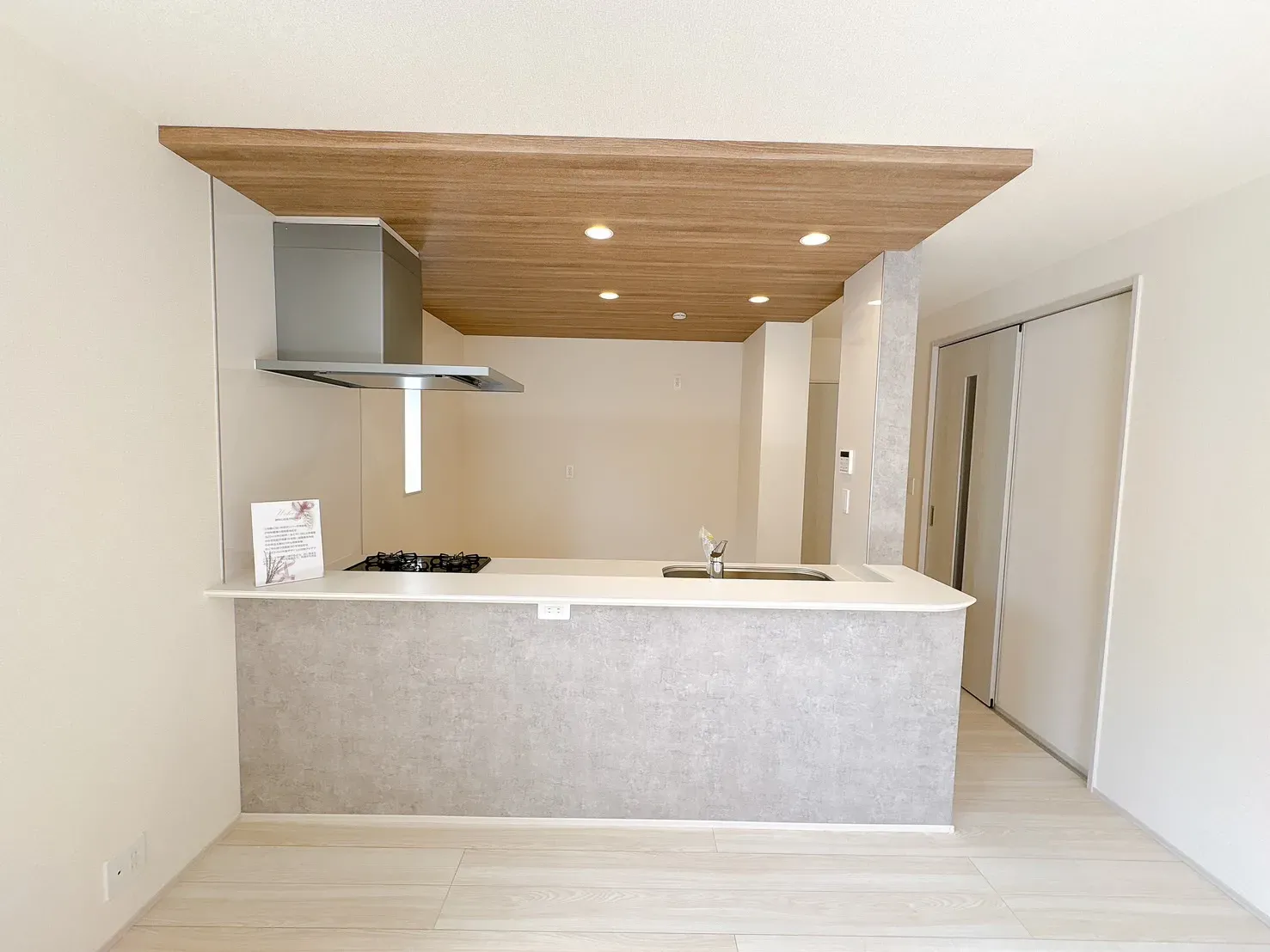 【キッチン前面】ご家族やゲストと会話が弾む対面式キッチンを採用。キッチン上部は空間にメリハリを演出するポップアップ天井を施しています。