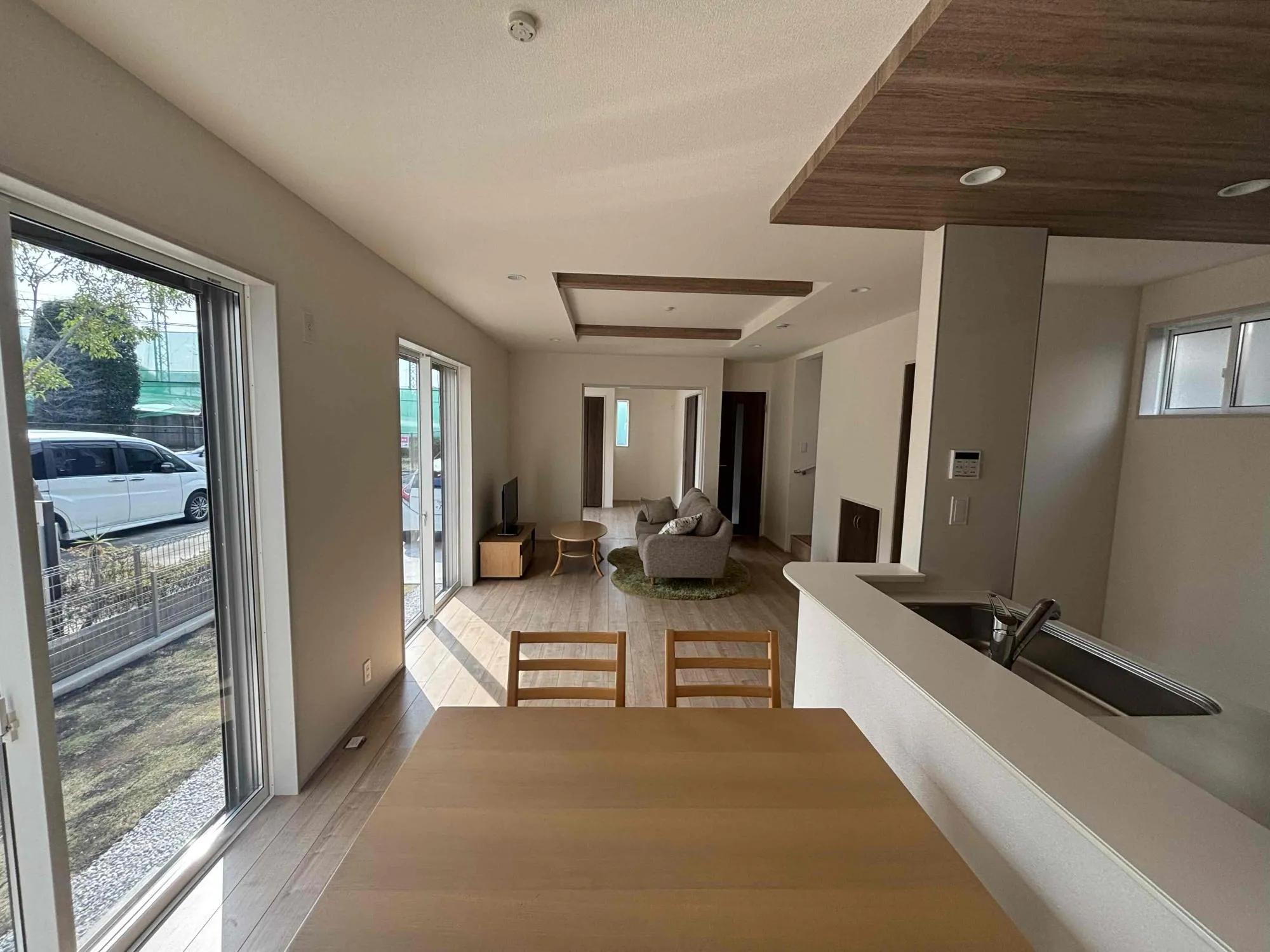 キッチン部分と折上天井の梁部分に同一の木目調のアクセントクロスでリビングに統一感を出しました